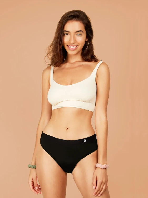 Czarne majtki menstruacyjne Fluxies Hipster na kobiecie w kremowym topie, widok z przodu