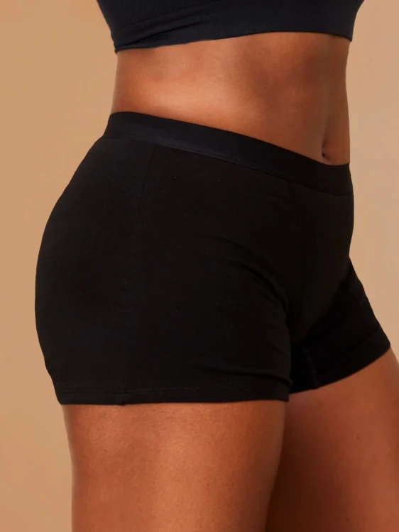 Zbliżenie na czarne majtki menstruacyjne Fluxies Sleep Short na kobiecej sylwetce, widok z boku