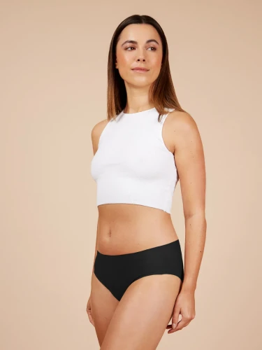 Kobieta w białym topie i czarnych majtkach menstruacyjnych Fluxies NuStretch