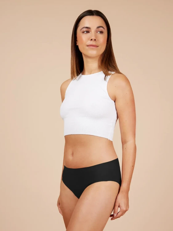 Kobieta w białym topie i czarnych majtkach menstruacyjnych Fluxies NuStretch